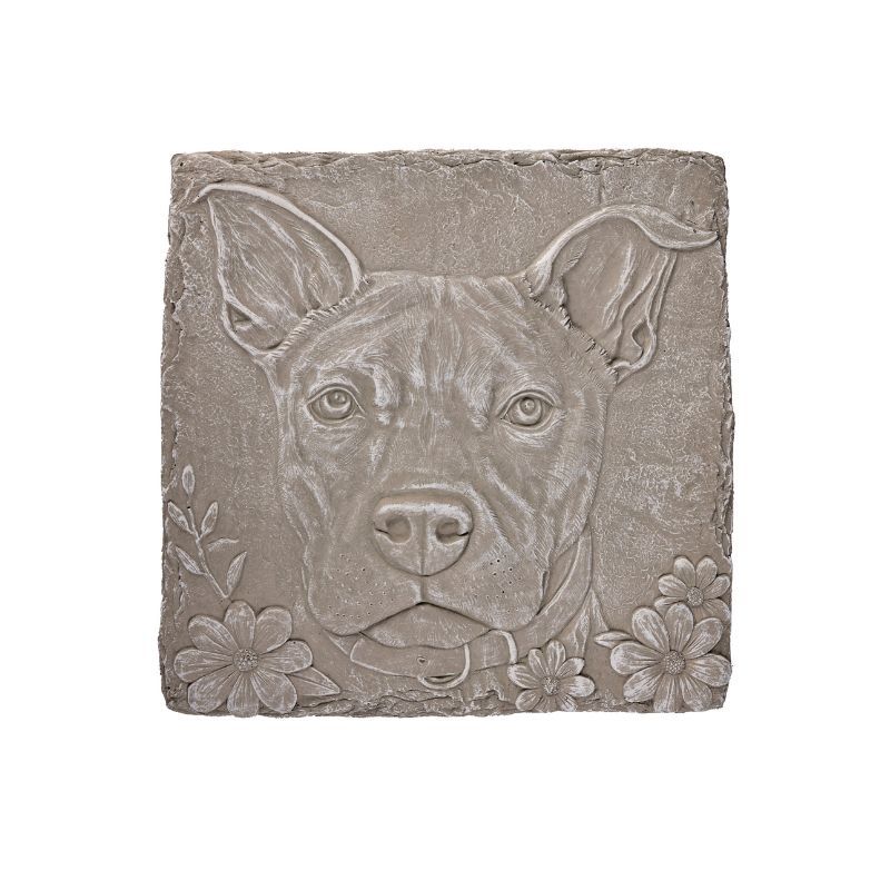 Dog face relief sculpture on a square stone, with flowers around the edges.