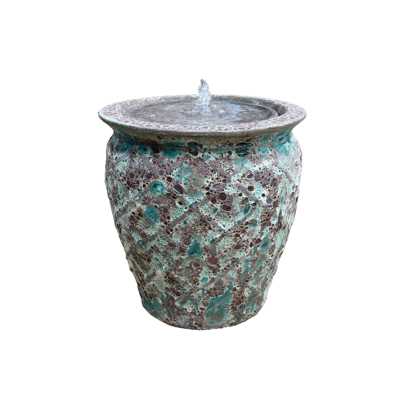 Blue-green mosaic water fountain. Water streams from the center, flowing into the basin.