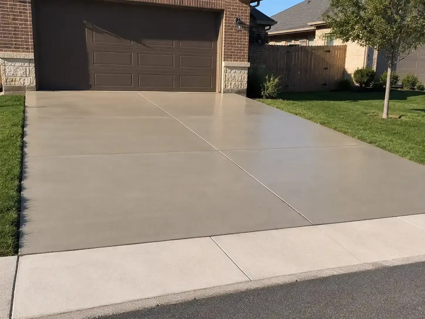 Wet concrete driveway leading to a closed garage in a suburban home.