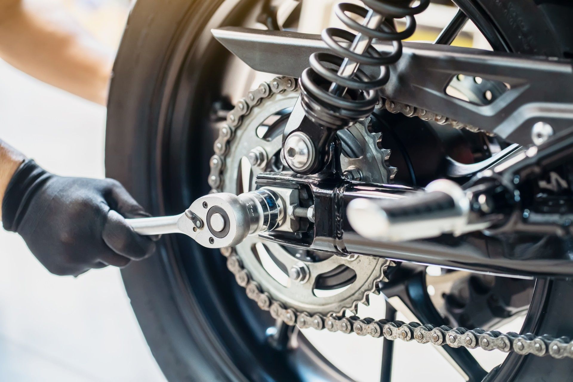 A man is fixing a motorcycle with a wrench.