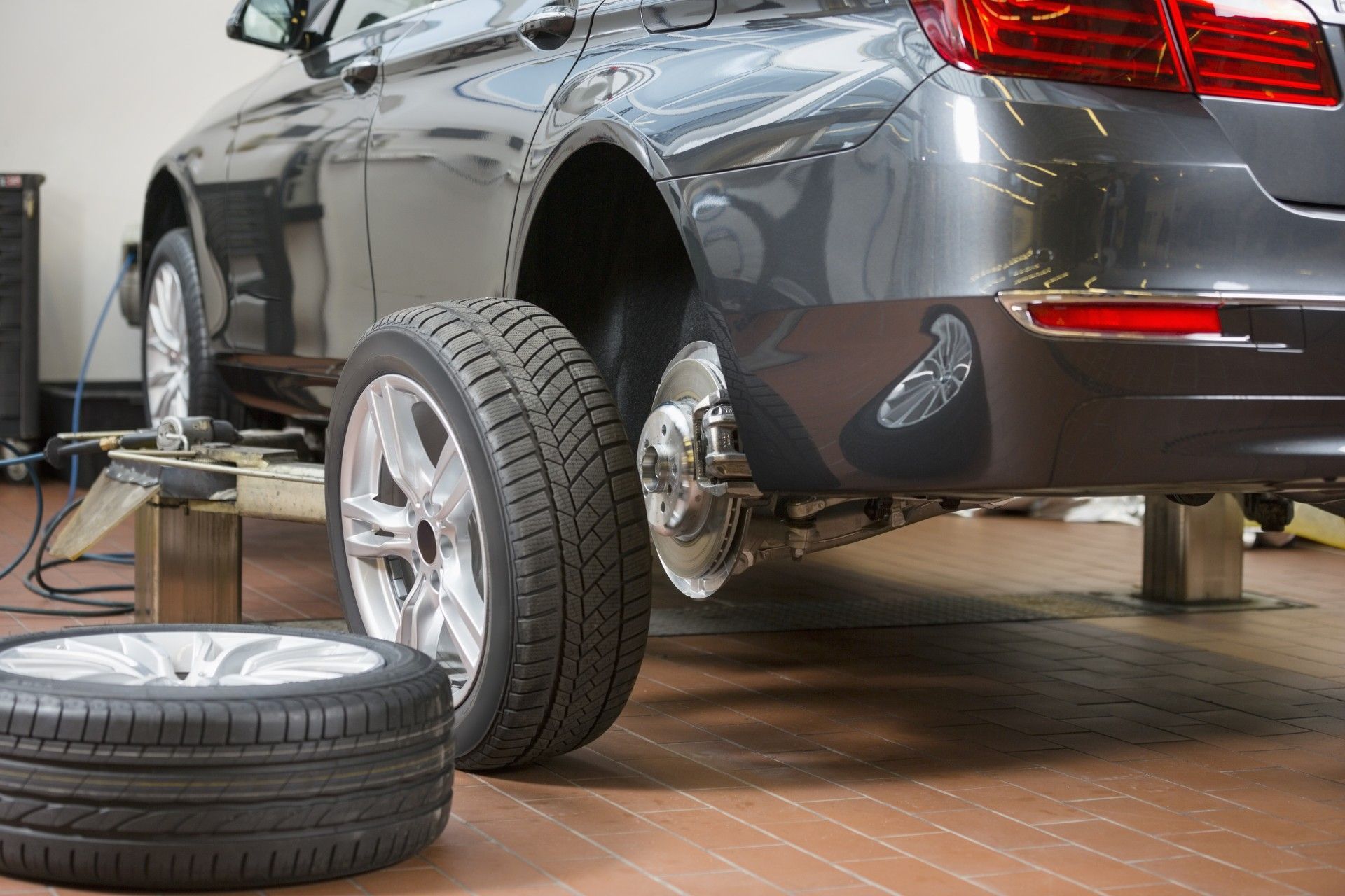 A car is being repaired in a garage with tires on the ground.