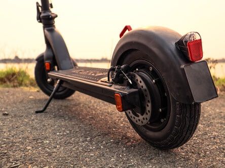 A black electric scooter is parked on the side of a road.
