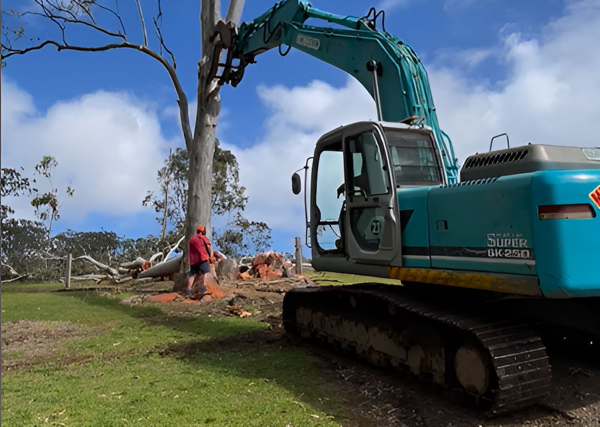 A Large Green Excavator Is Parked In A Grassy Field — GCE Earthworks Pty Ltd In Krambach, NSW