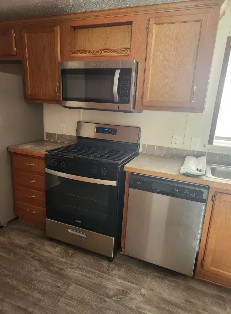 Kitchen with oven, microwave, dishwasher, and wooden cabinets.
