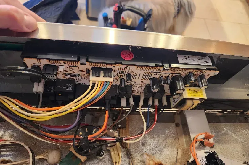 Close-up of appliance circuit board with multi-colored wires and electrical components.