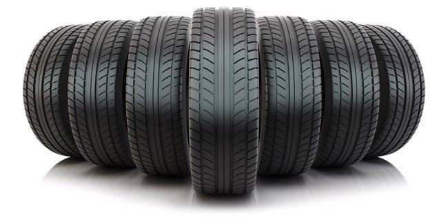 A group of tires are stacked on top of each other on a white surface.