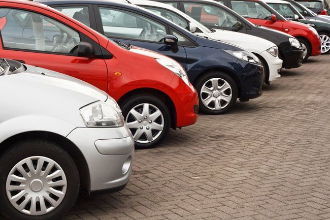A row of cars are parked in a parking lot.