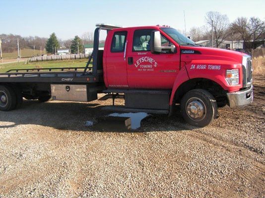 A red tow truck is parked in a gravel lot