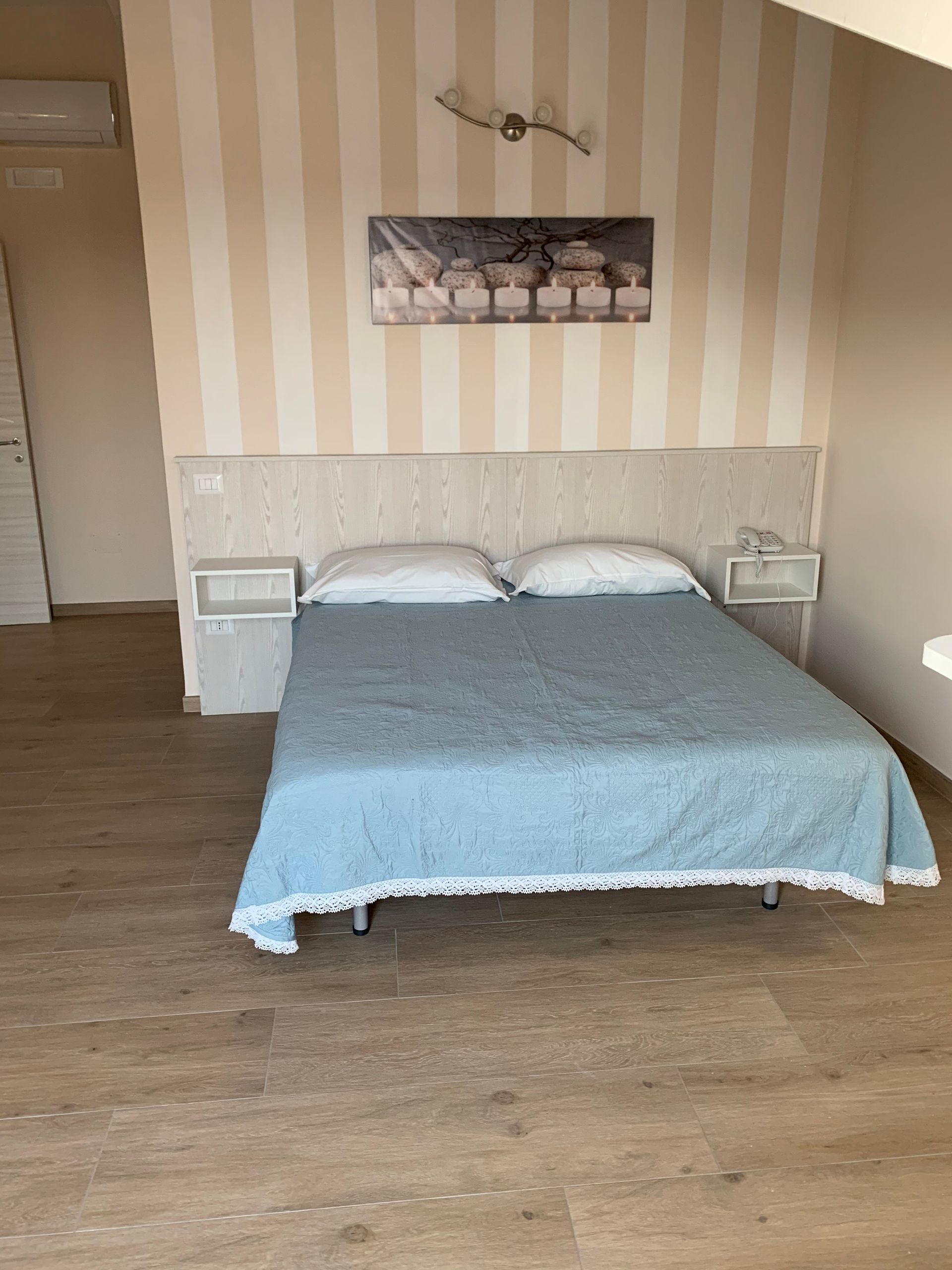 Camera da letto vuota con letto, carta da parati a righe e pavimento in legno.