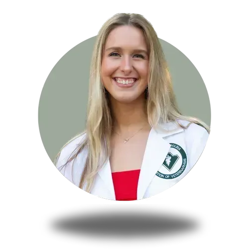 Smiling woman in a white coat with a green emblem, wearing a red top on a light gray background