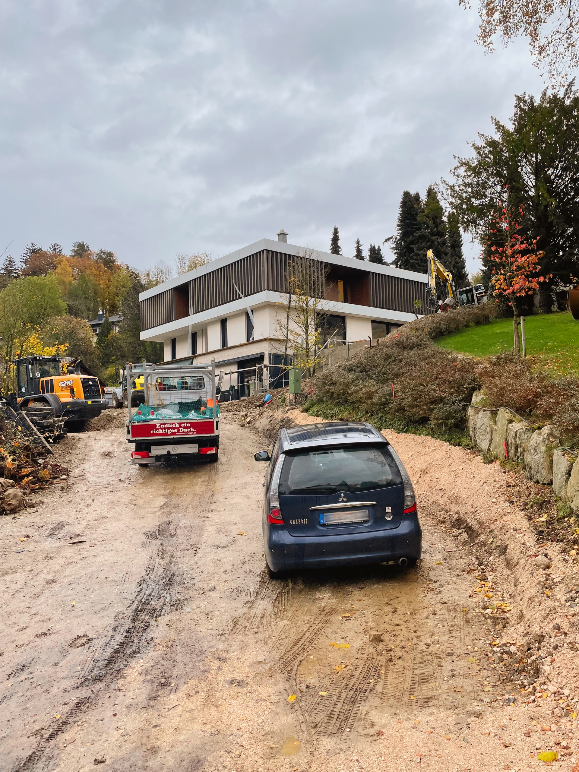 Zwei Autos fahren eine schlammige Straße vor einem Gebäude entlang