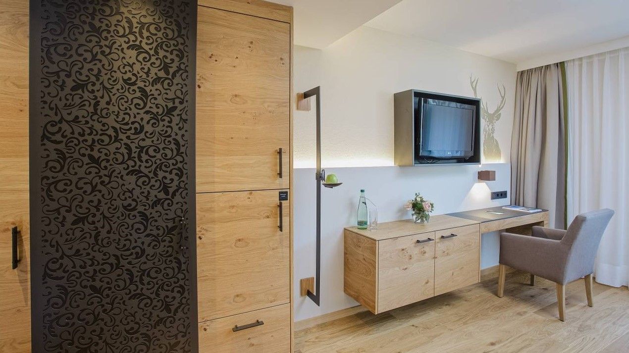 Ein Hotelzimmer mit einem Schreibtisch, einem Stuhl und einem Flachbildfernseher