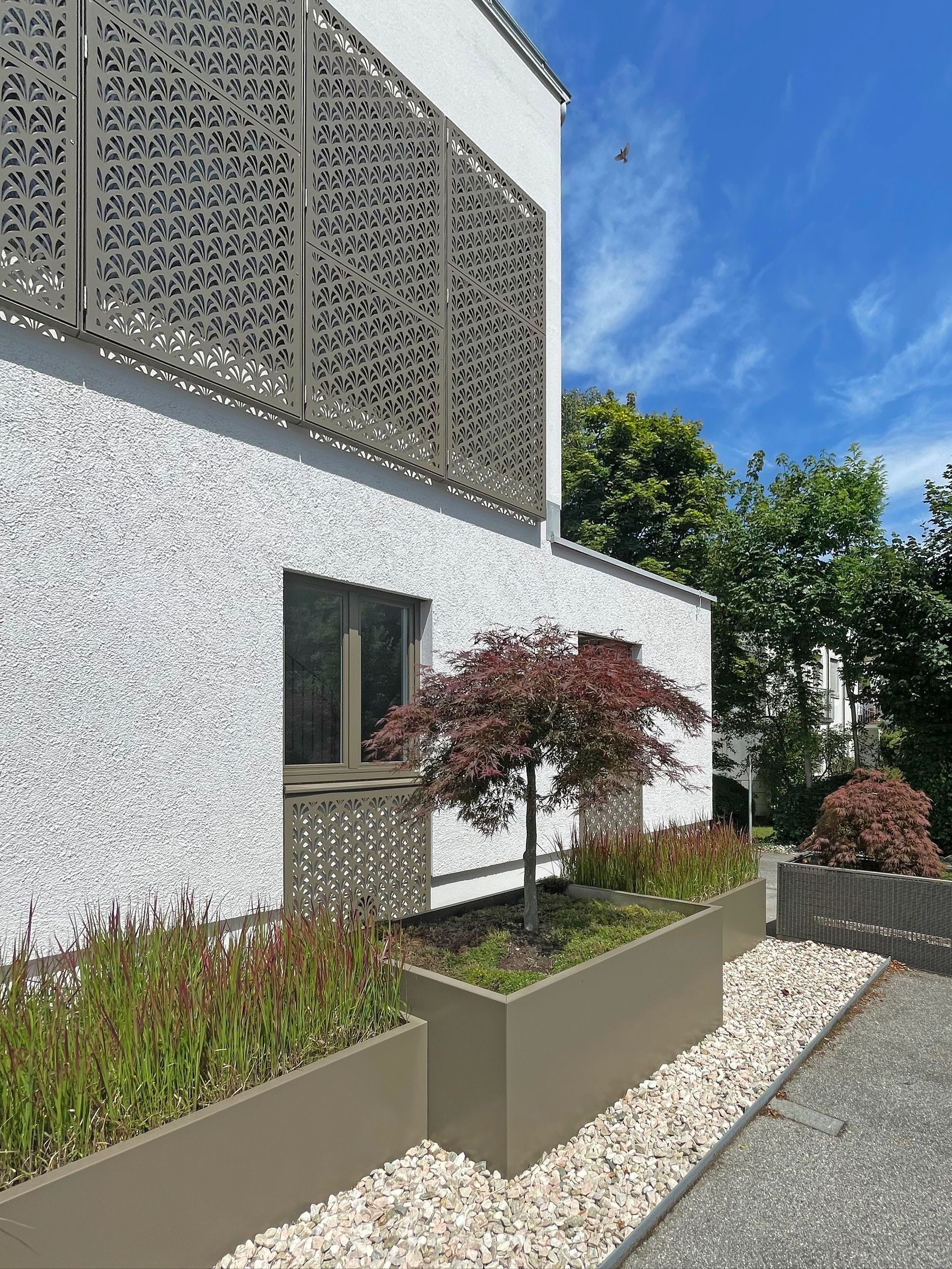 Ein weißes Gebäude mit vielen Pflanzkübeln davor