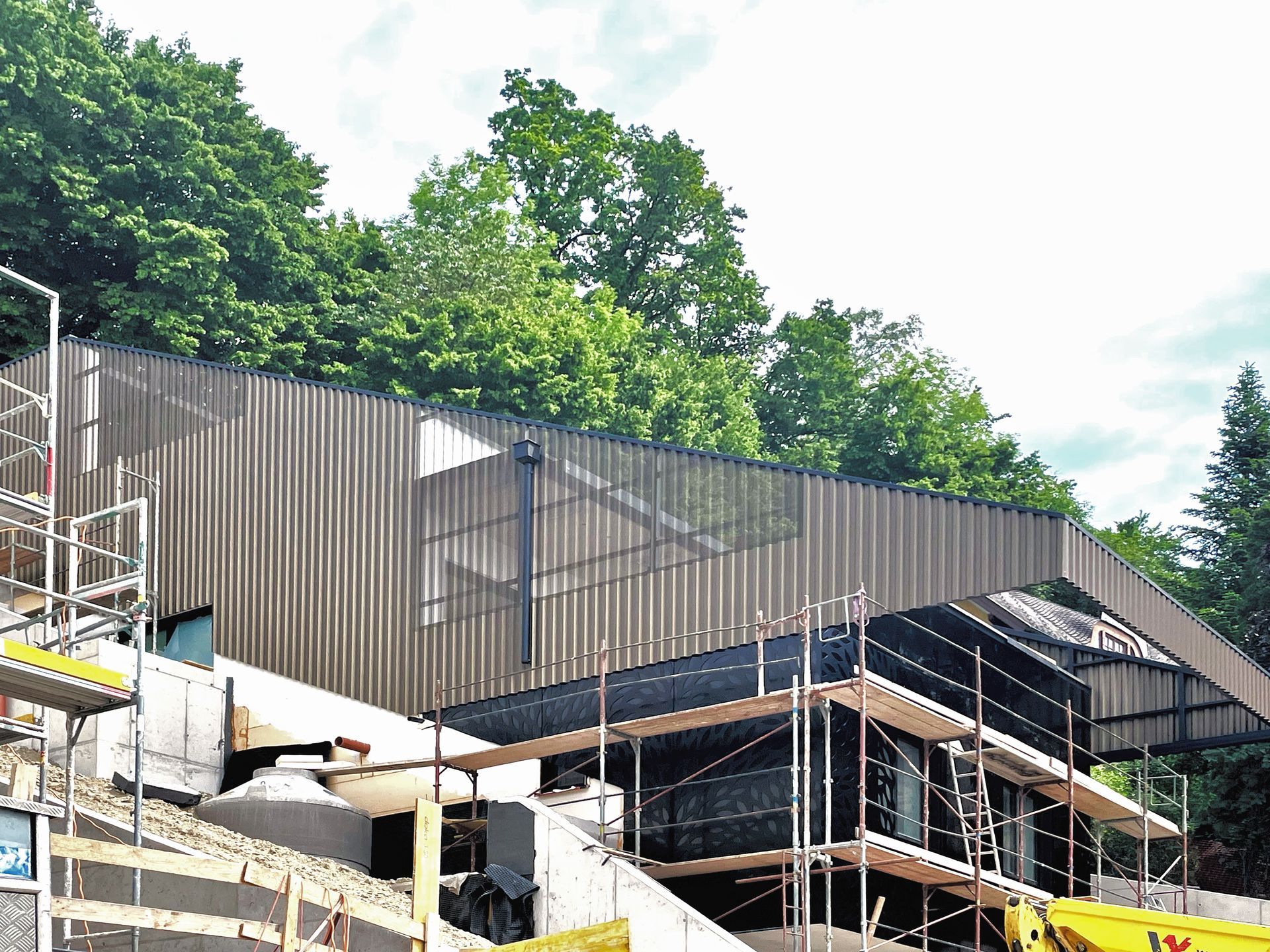 Ein großes Gebäude wird mit Gerüsten und Bäumen im Hintergrund gebaut