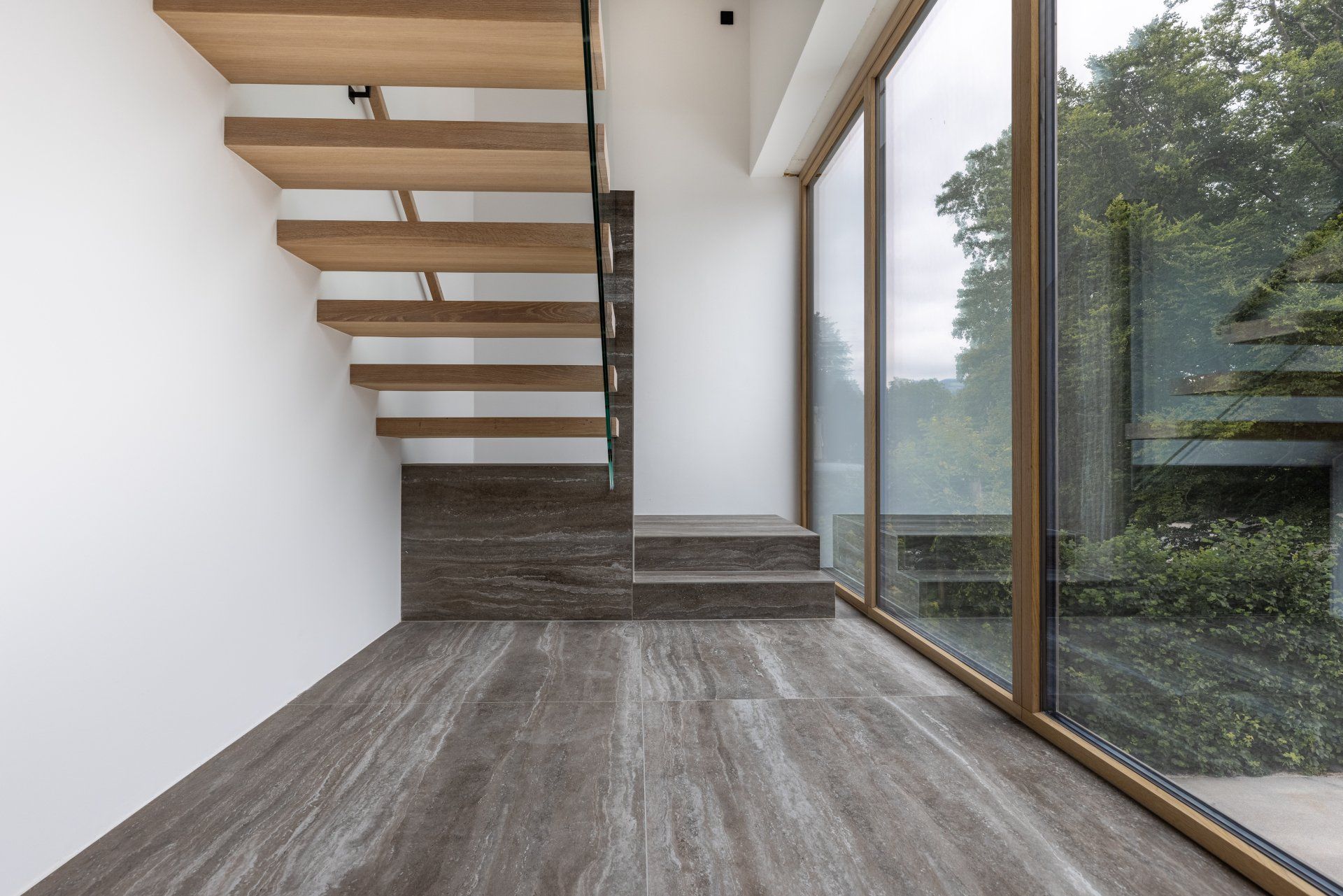Ein leerer Raum mit einer Holztreppe und einem großen Fenster