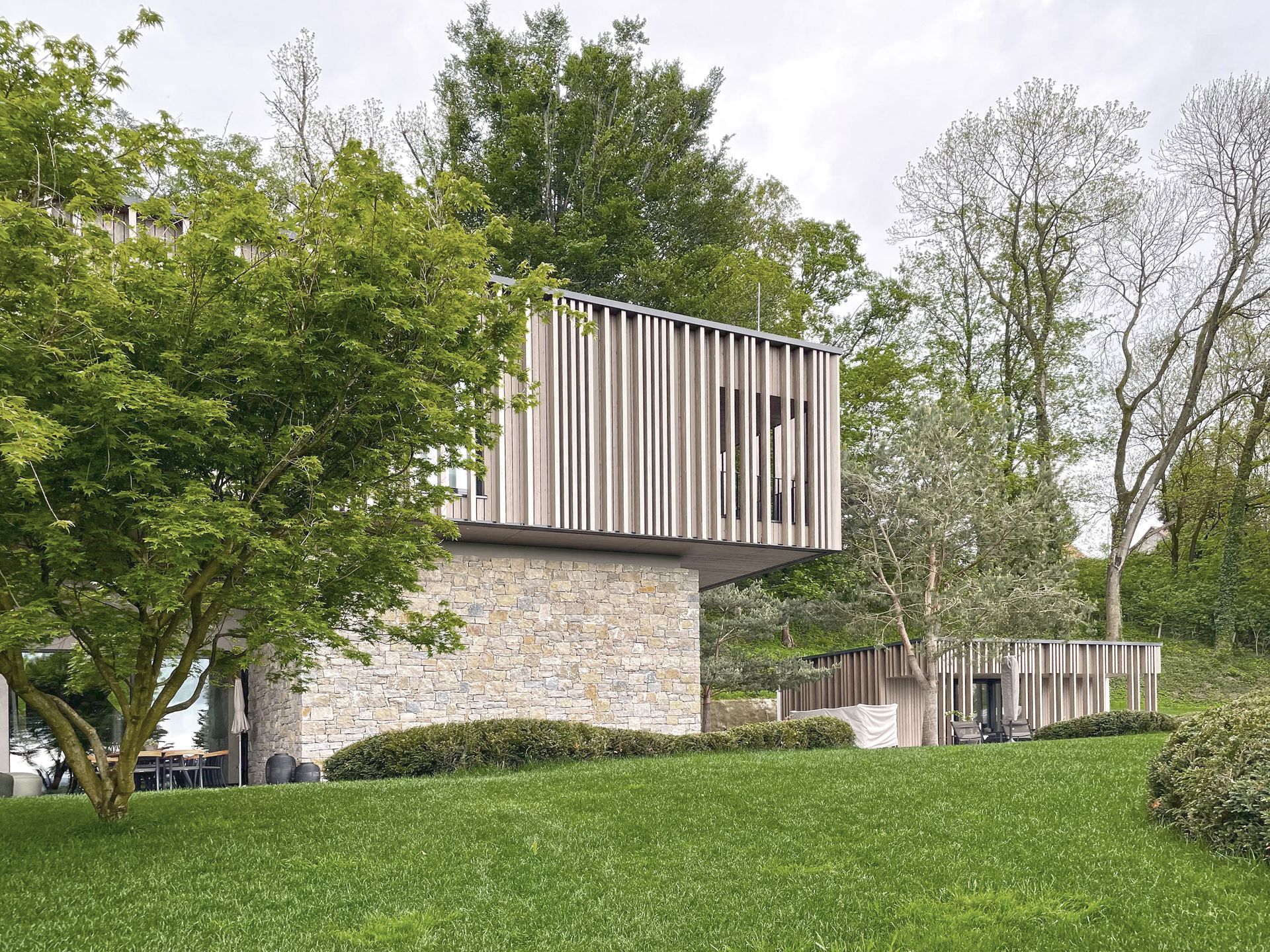 Ein Haus mit Holzdach ist von Bäumen und Gras umgeben.