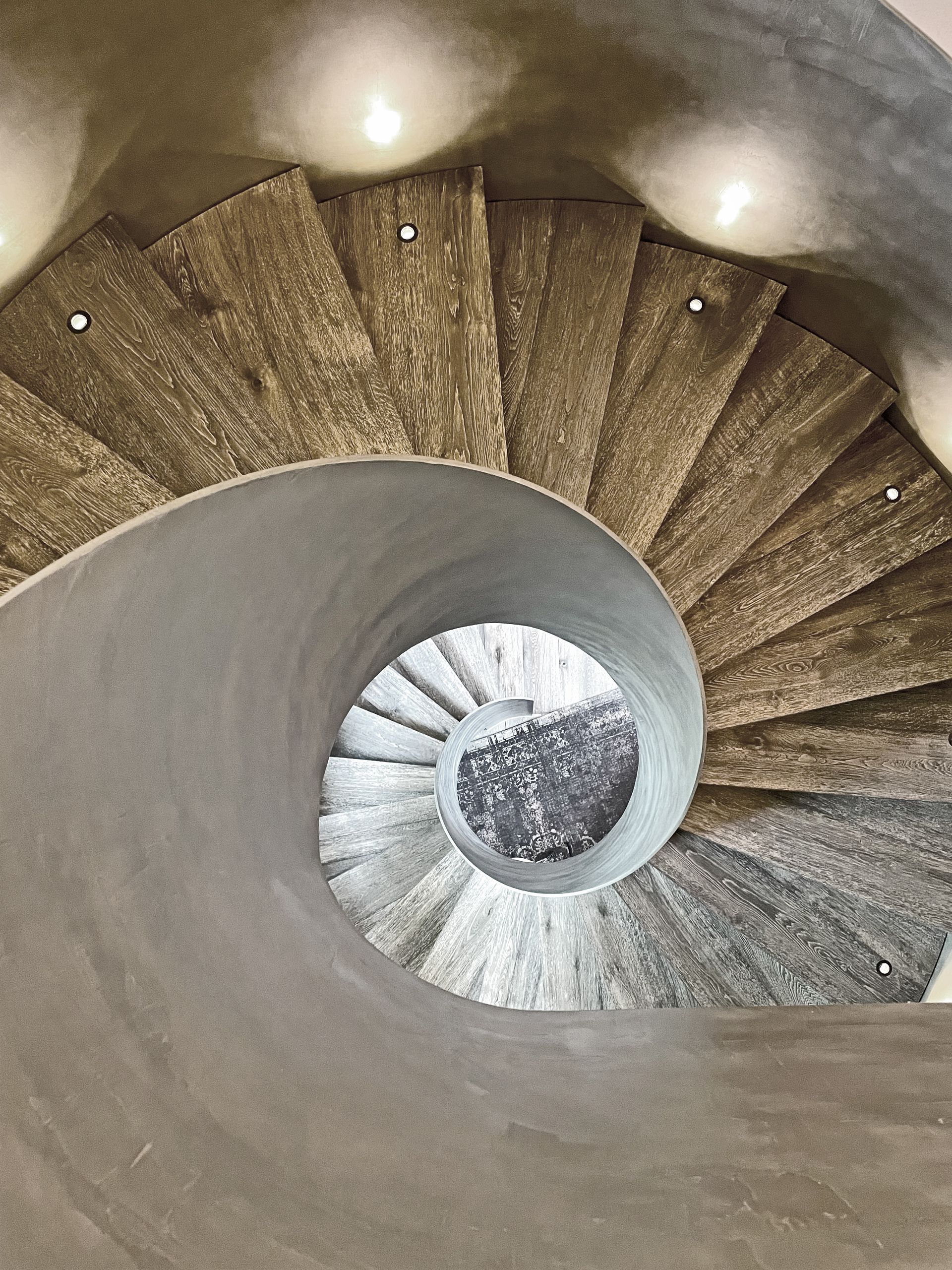 Blick nach unten auf eine Wendeltreppe mit Lichtern auf den Stufen