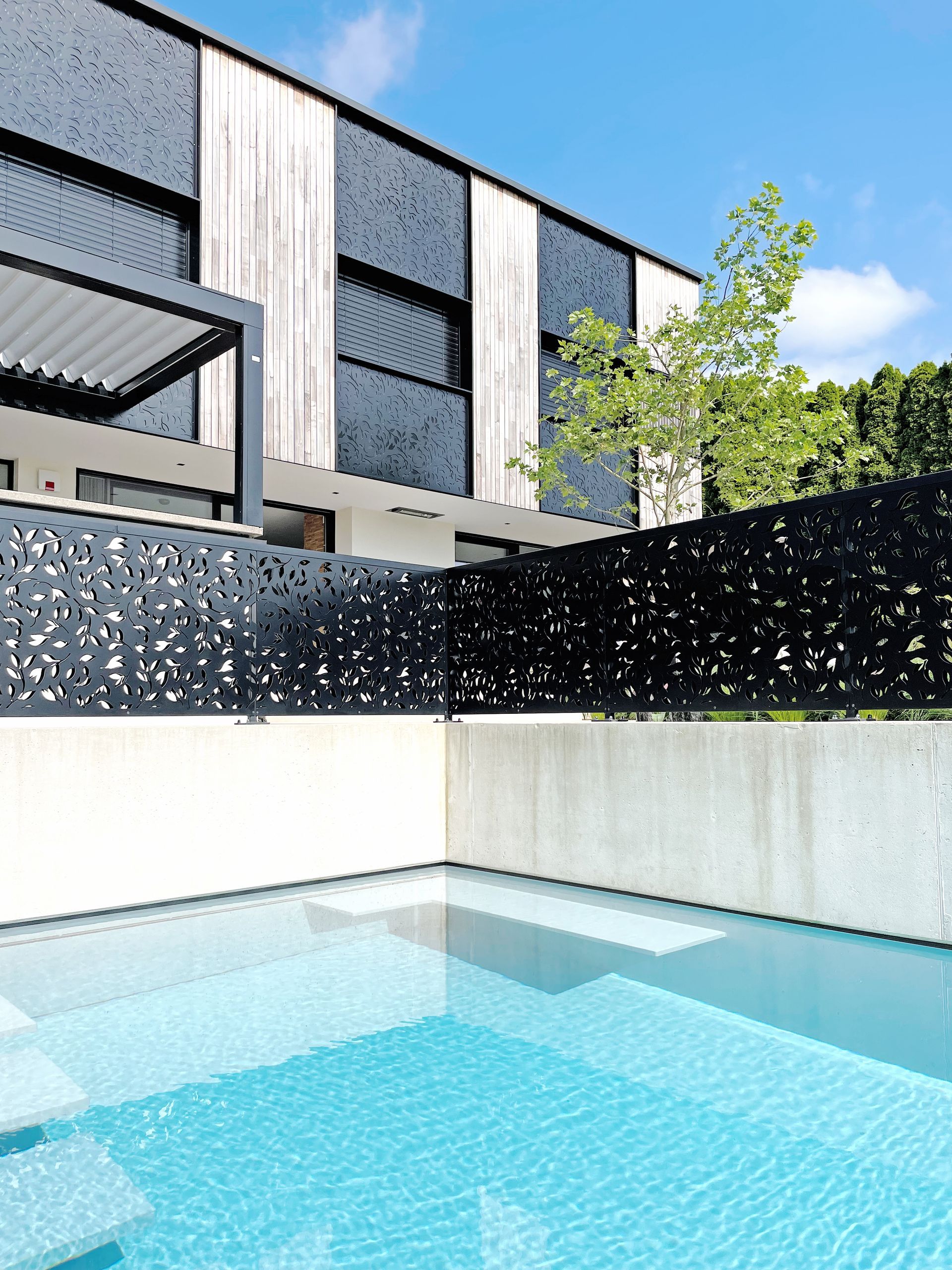 Ein Swimmingpool vor einem Gebäude mit einem schwarzen Zaun