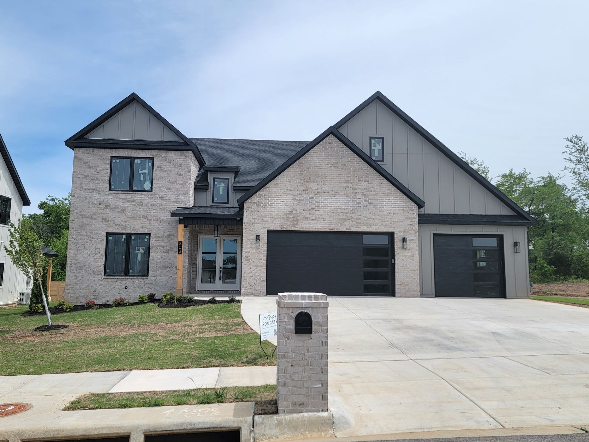 Two-story gray house with black garage doors and a concrete driveway