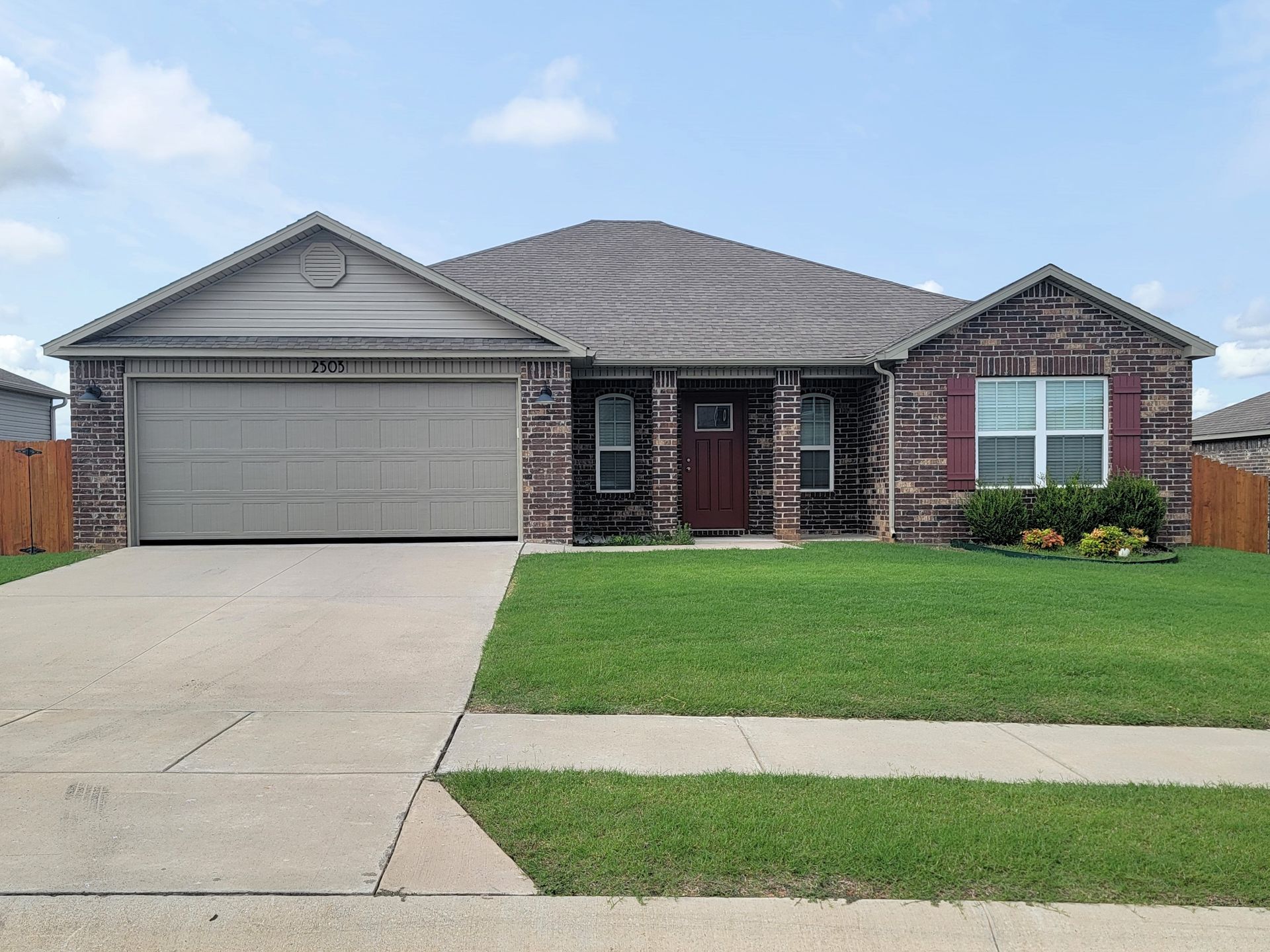 Suburban brick house with two-car garage, driveway, and neatly trimmed front lawn