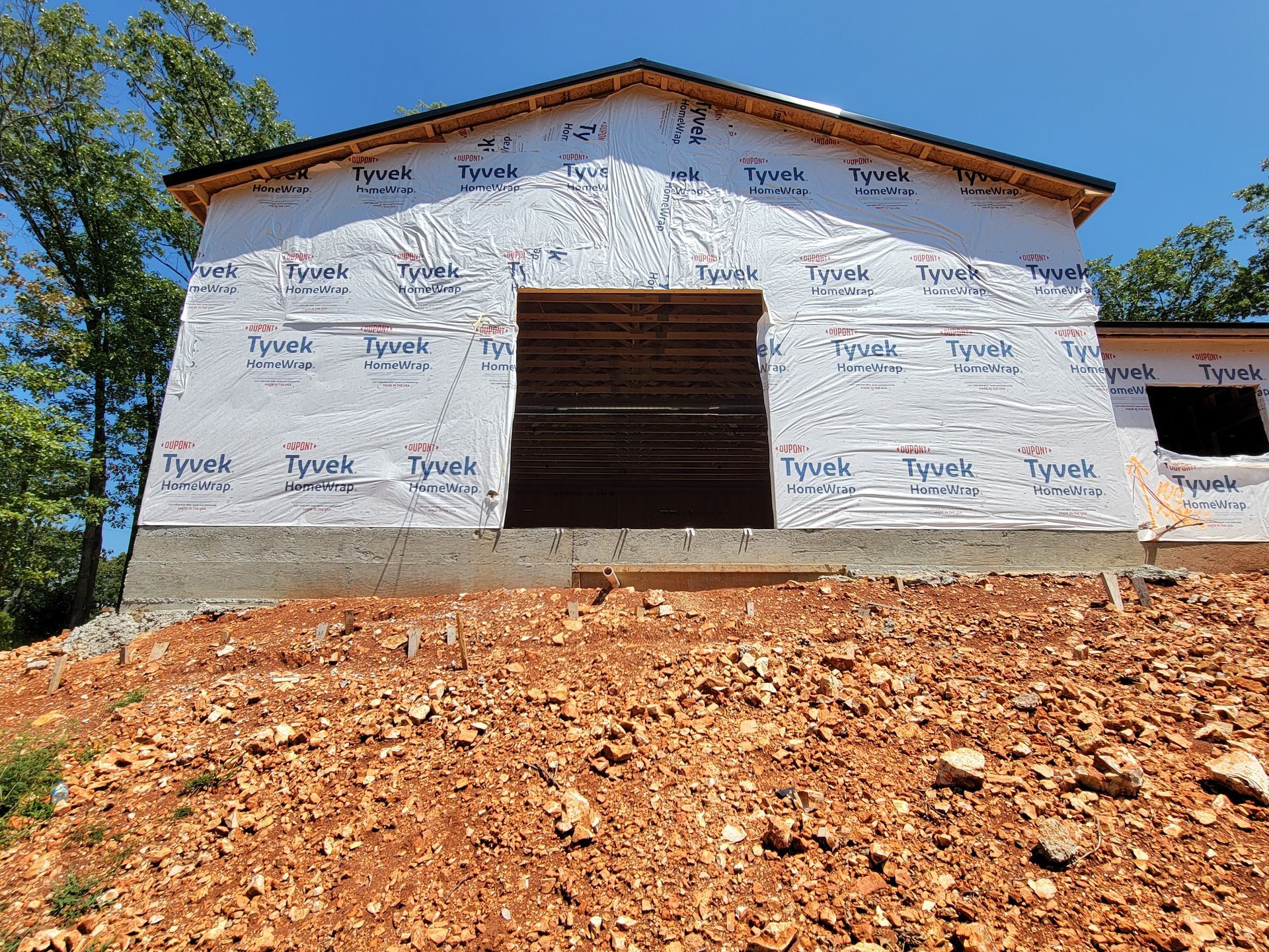 White building under construction with exposed wooden doorway and dirt foreground