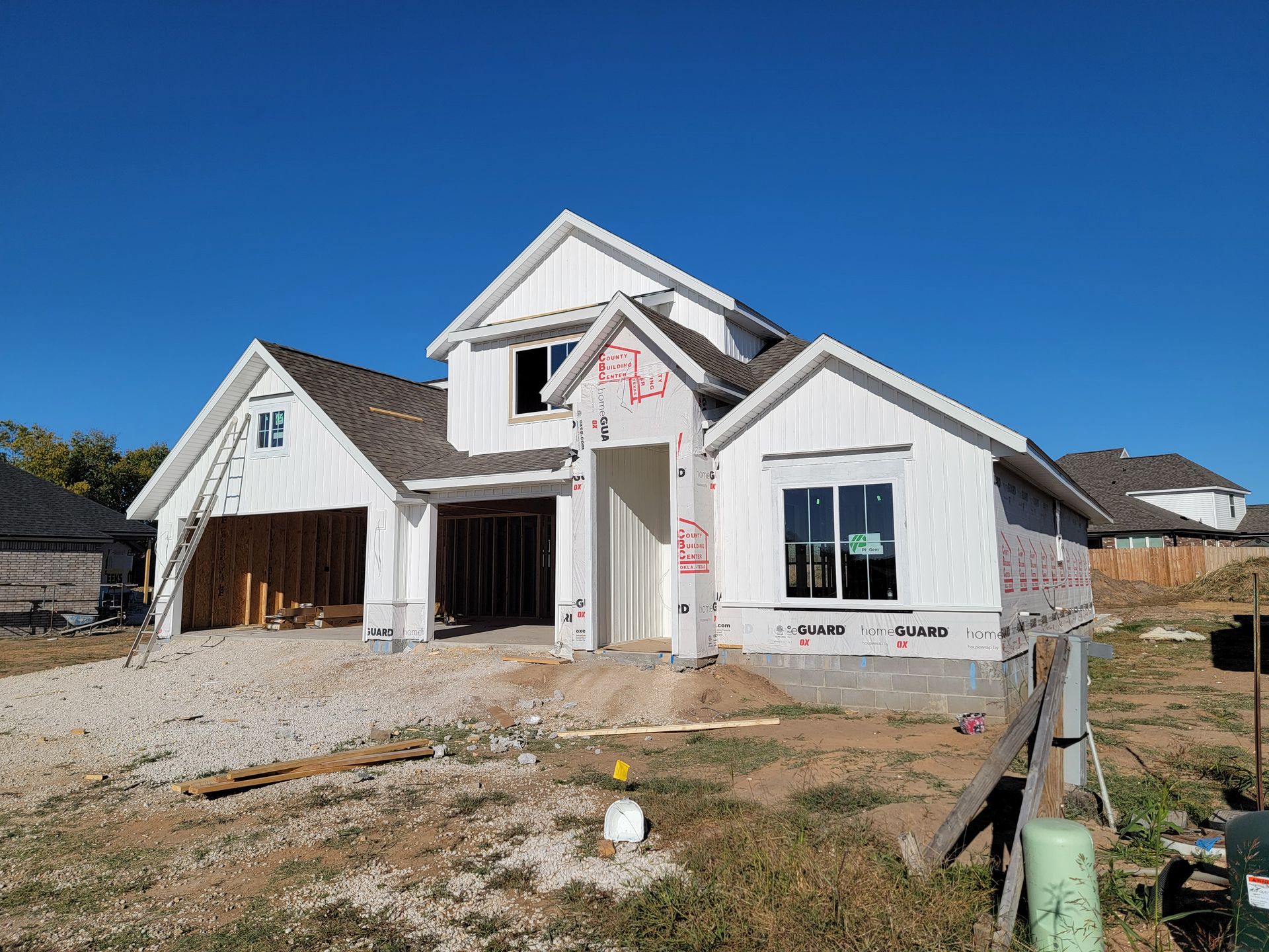 New white house under construction with unfinished driveway and blue sky