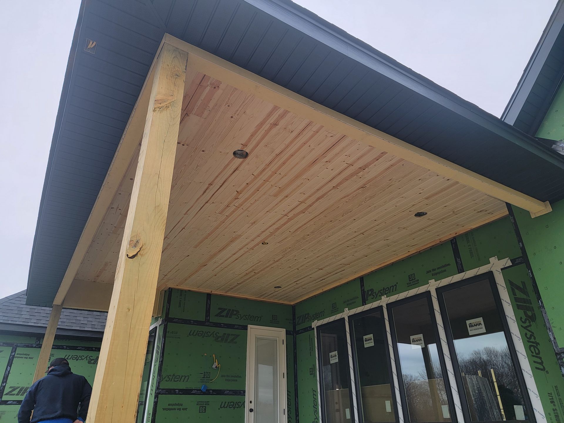Building entrance with a covered wooden porch and glass doors, viewed from below