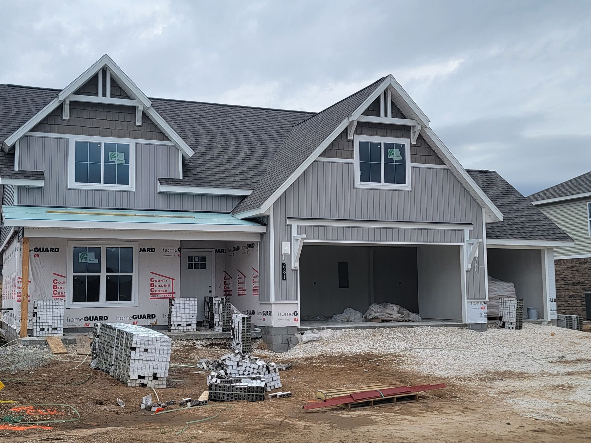 New gray house under construction with unfinished front yard and open garage.