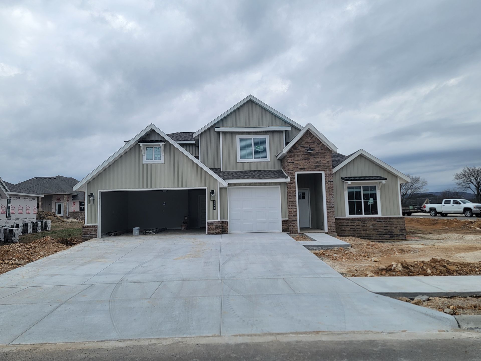 New suburban house with a three-car driveway under cloudy skies