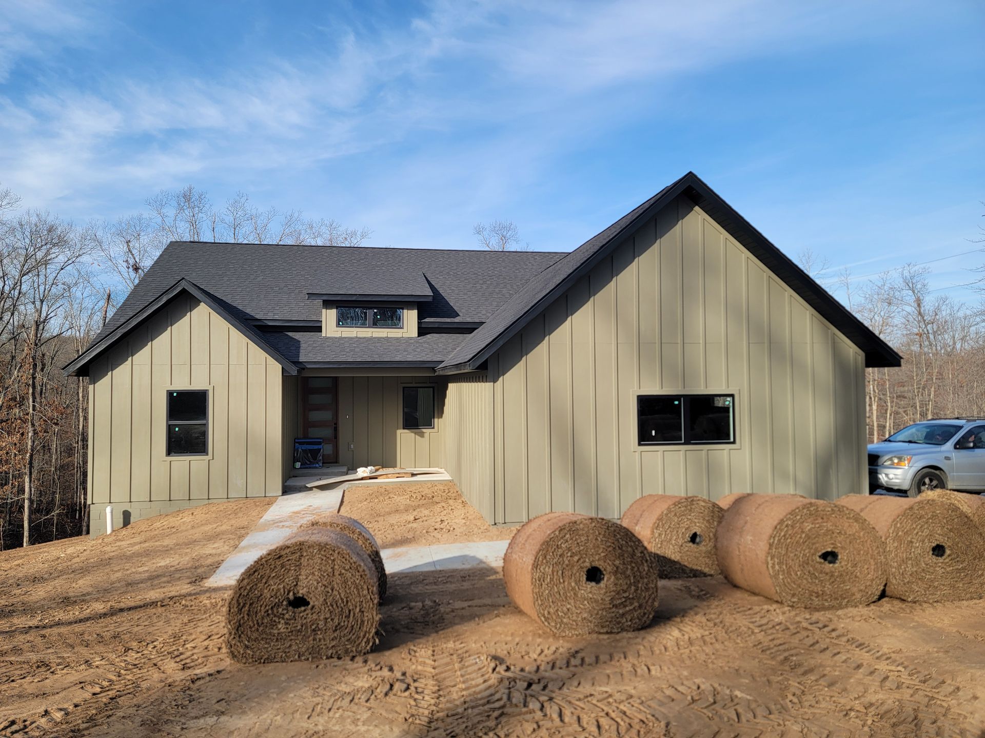New beige house under construction with straw bales in front and a blue sky