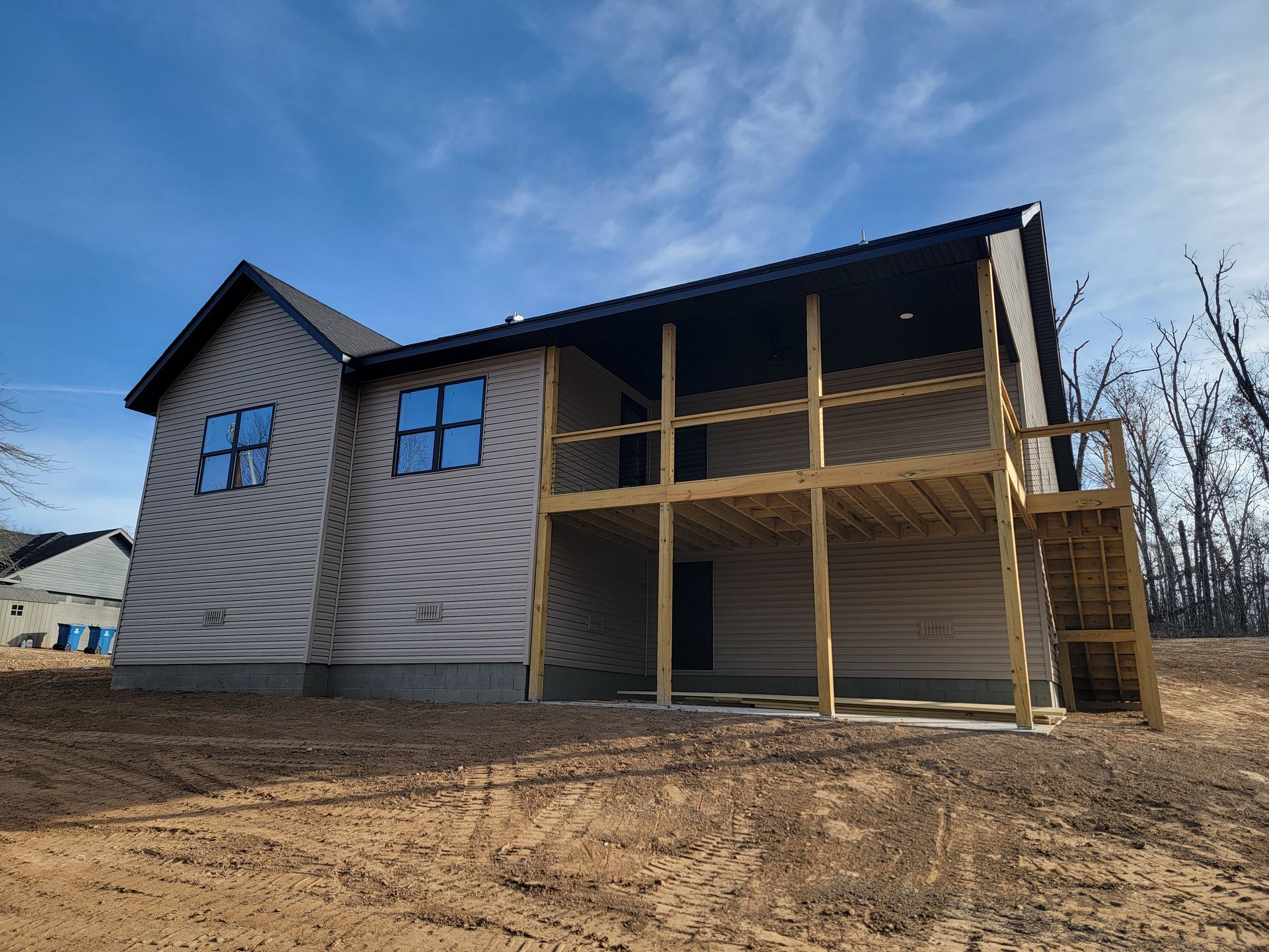 New house under construction with unfinished wooden porch on a dirt lot