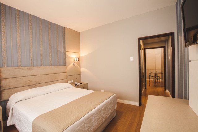 Um quarto de hotel com cama king size e televisão.