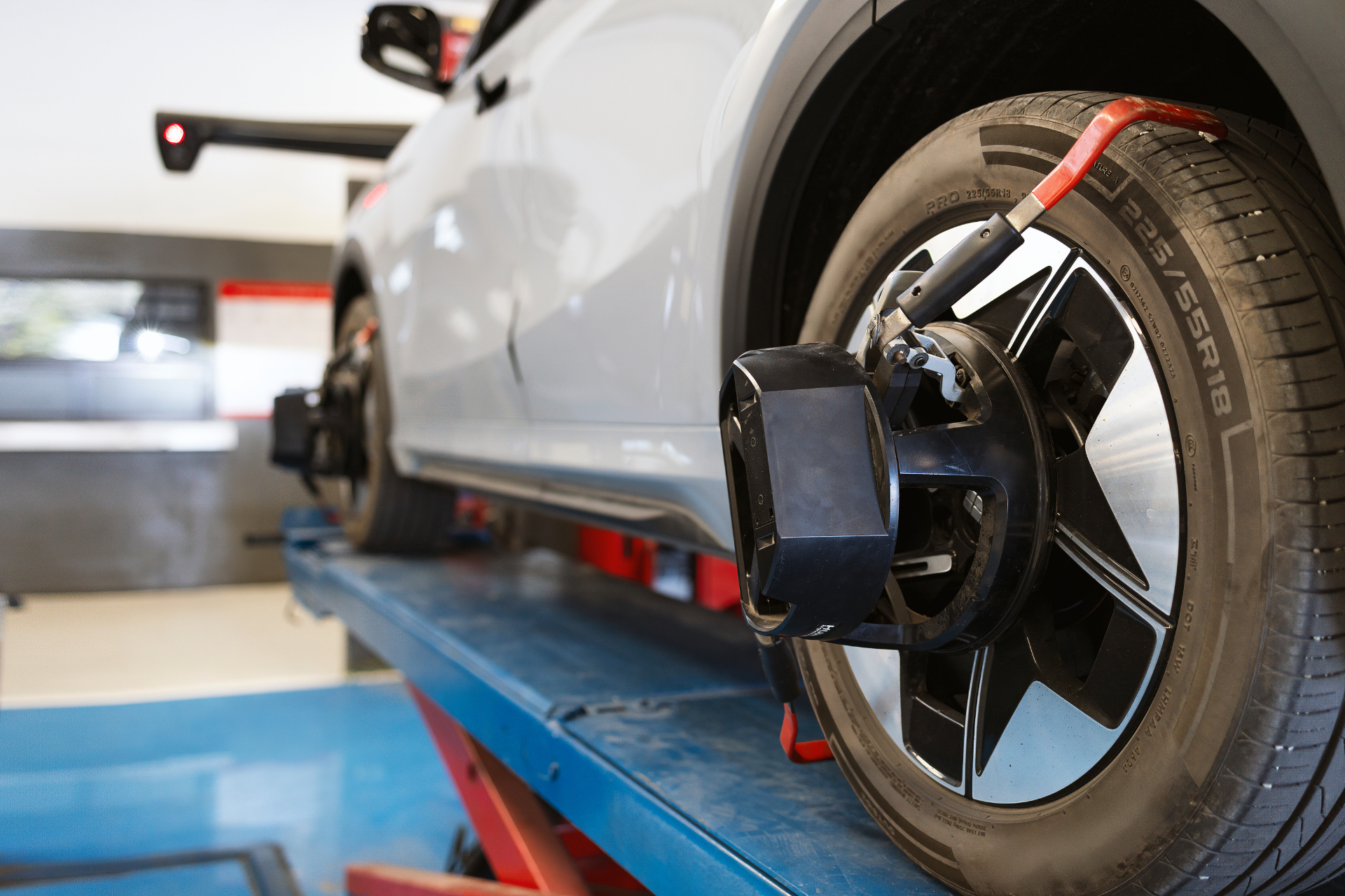 Car on a lift with alignment tools attached to wheels, in a shop.