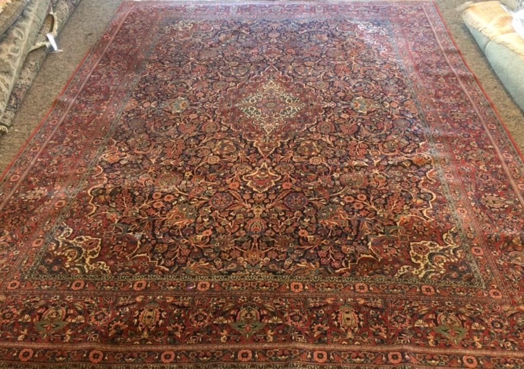 Red and dark rug with floral designs, viewed from above in a room.