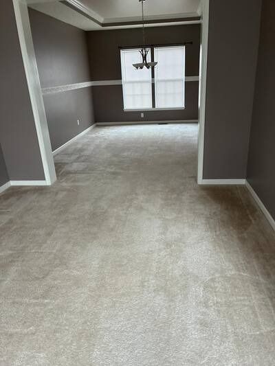 Empty carpeted room with gray walls and a window at the far end