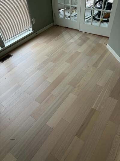 Empty room with light wood flooring, window blinds, and mirrored closet doors