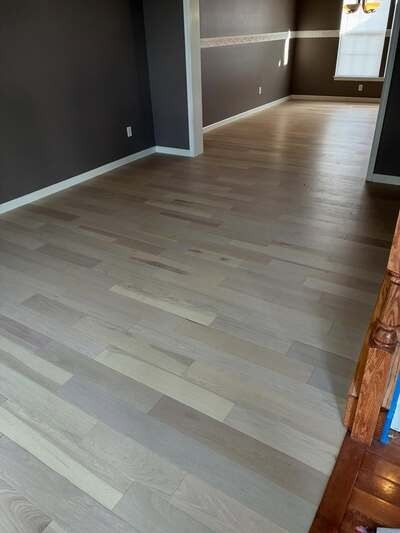 Empty room with light wood floors, dark walls, and doorway to a bright hallway