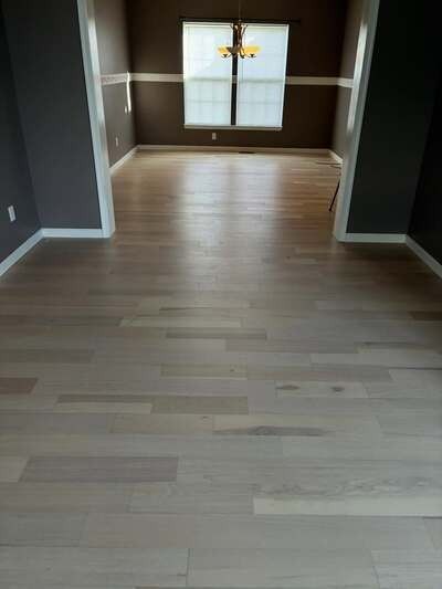 Empty room with light wood floors and a window at the far end
