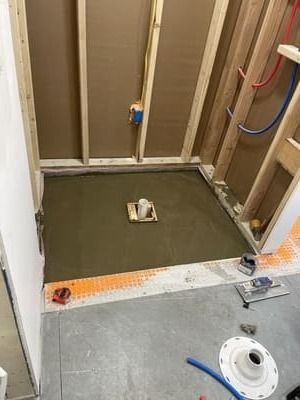 Bathroom under renovation with exposed wall studs and a recessed shower pan on the floor.