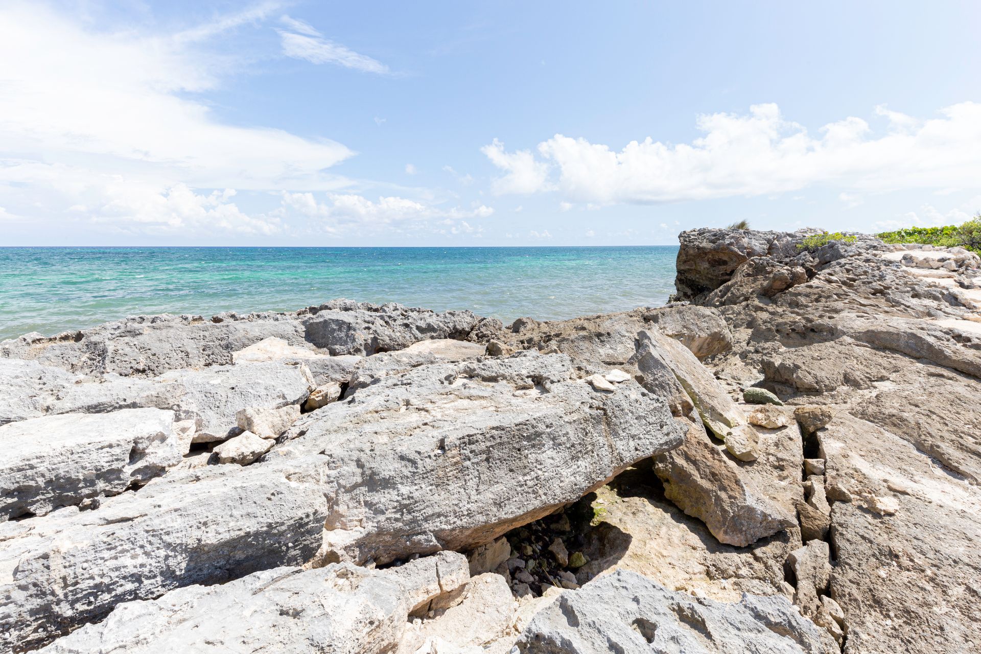 Rocky shoreline with turquoise ocean and bright sky on a sunny day