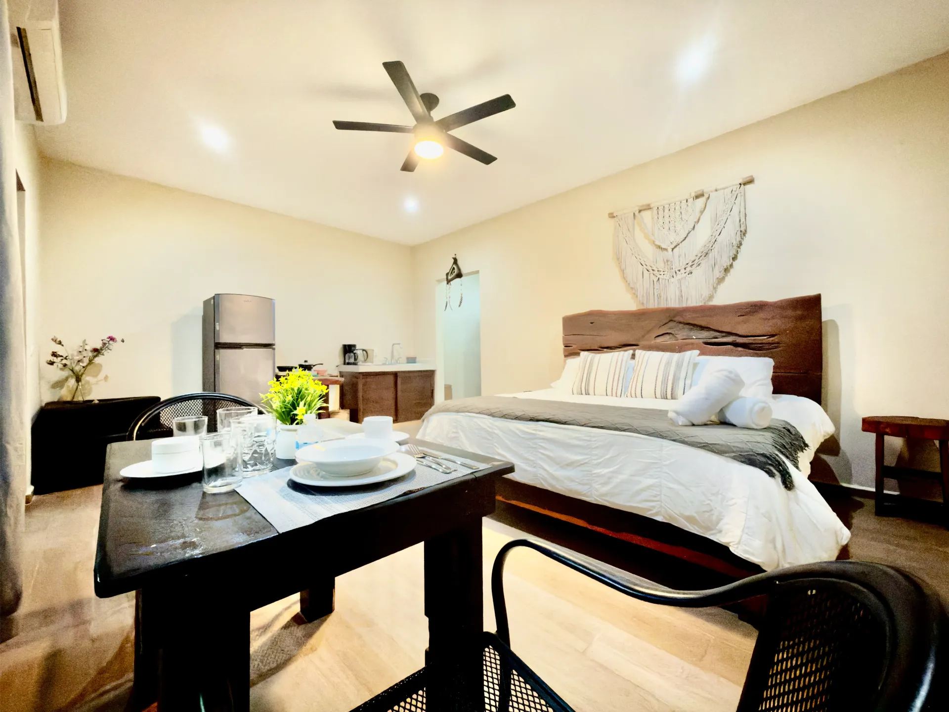 Modern bedroom with a bed, dark wooden table, ceiling fan, and soft beige decor