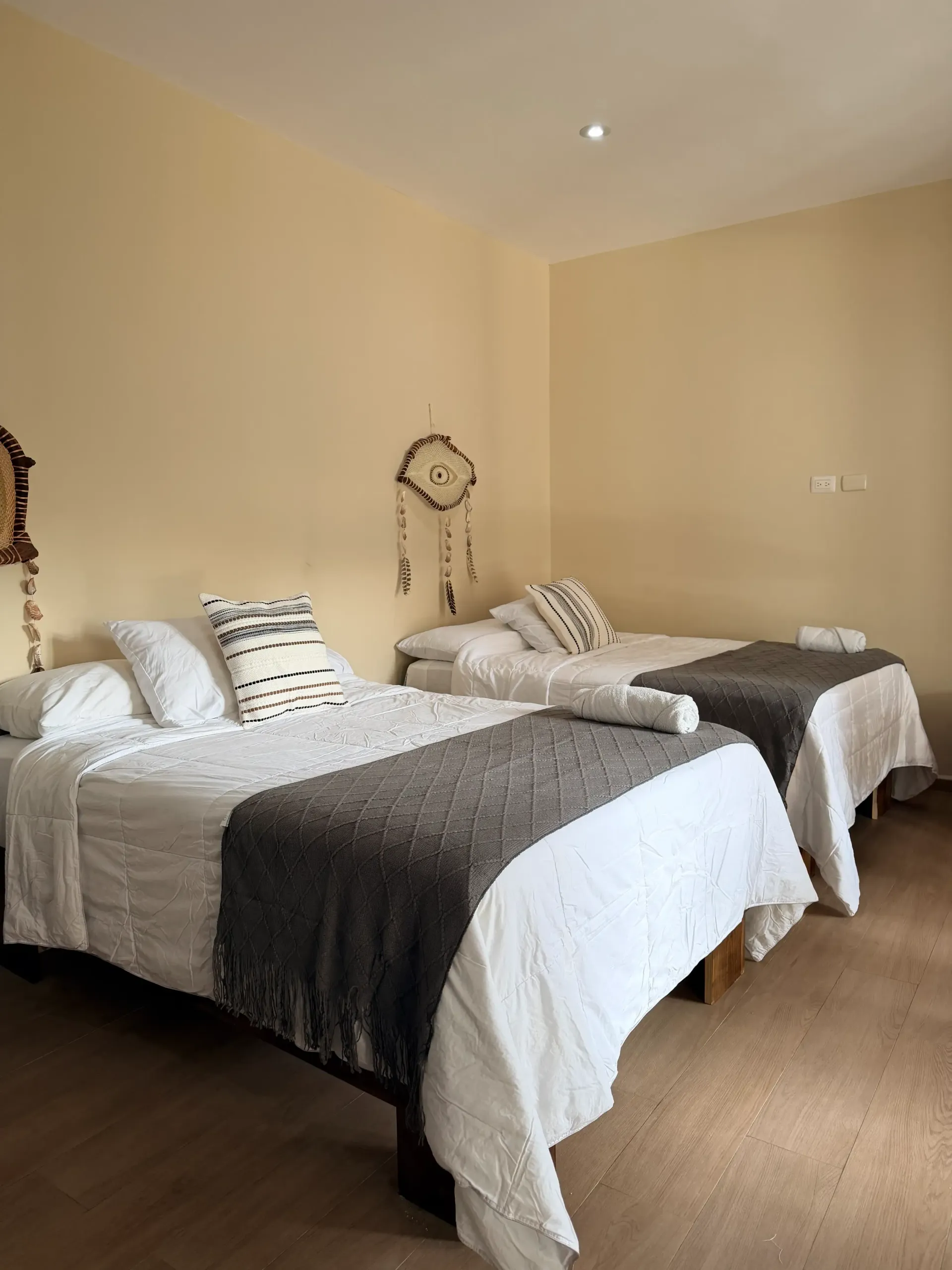 Two twin beds with white bedding and gray throws in a beige hotel room