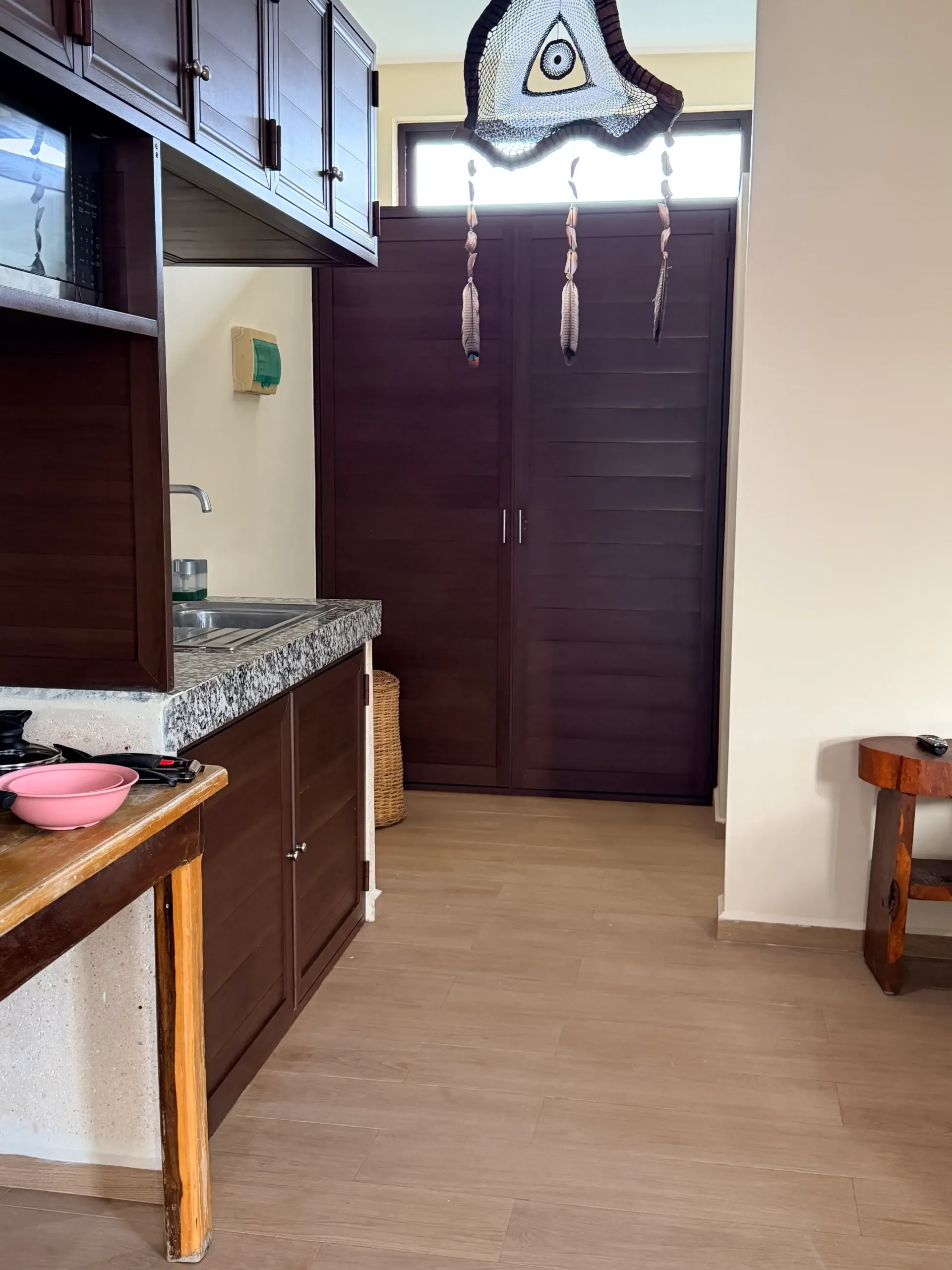 Kitchen interior with brown cabinets, granite countertop, and a closed dark wooden door at the back.