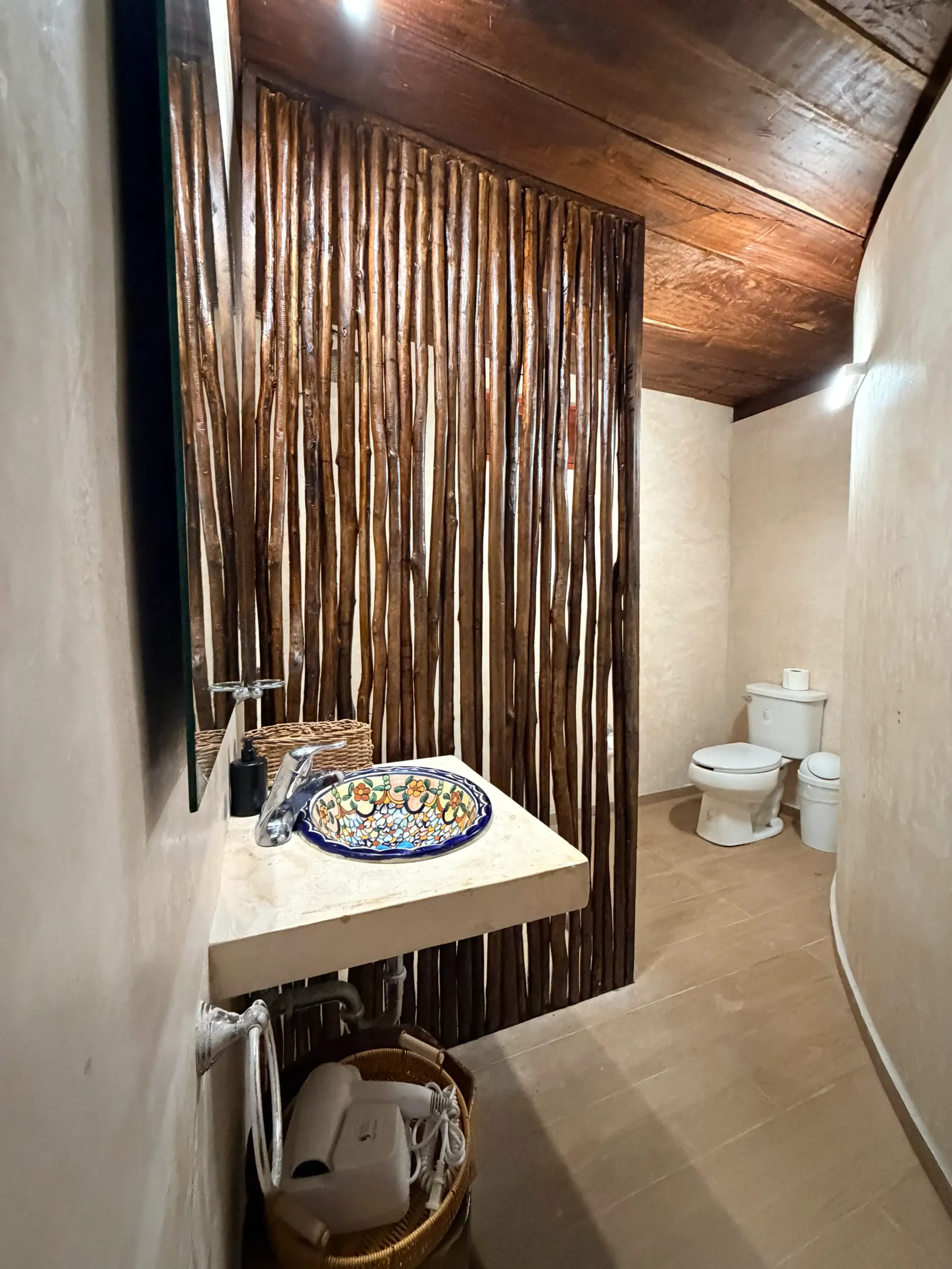 Small bathroom with a sink, toilet, and shower curtain under a slanted wooden ceiling.