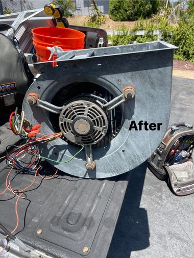 Air handler fan unit on truck bed with wires, tools, and bucket visible.