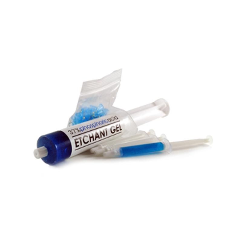 Una siringa contenente gel di acido fosforico al 37% e una piccola bustina di punte applicatrici, su uno sfondo bianco uniforme.