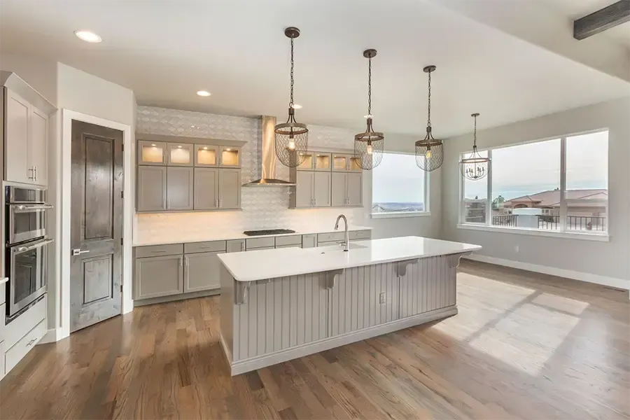Bright modern kitchen with a large island, pendant lights, white cabinets, and hardwood floors
