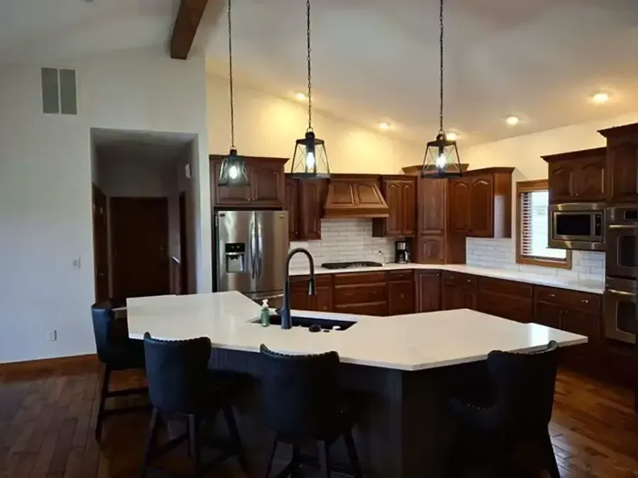 Modern kitchen with dark wood cabinets, white island, and hanging pendant lights