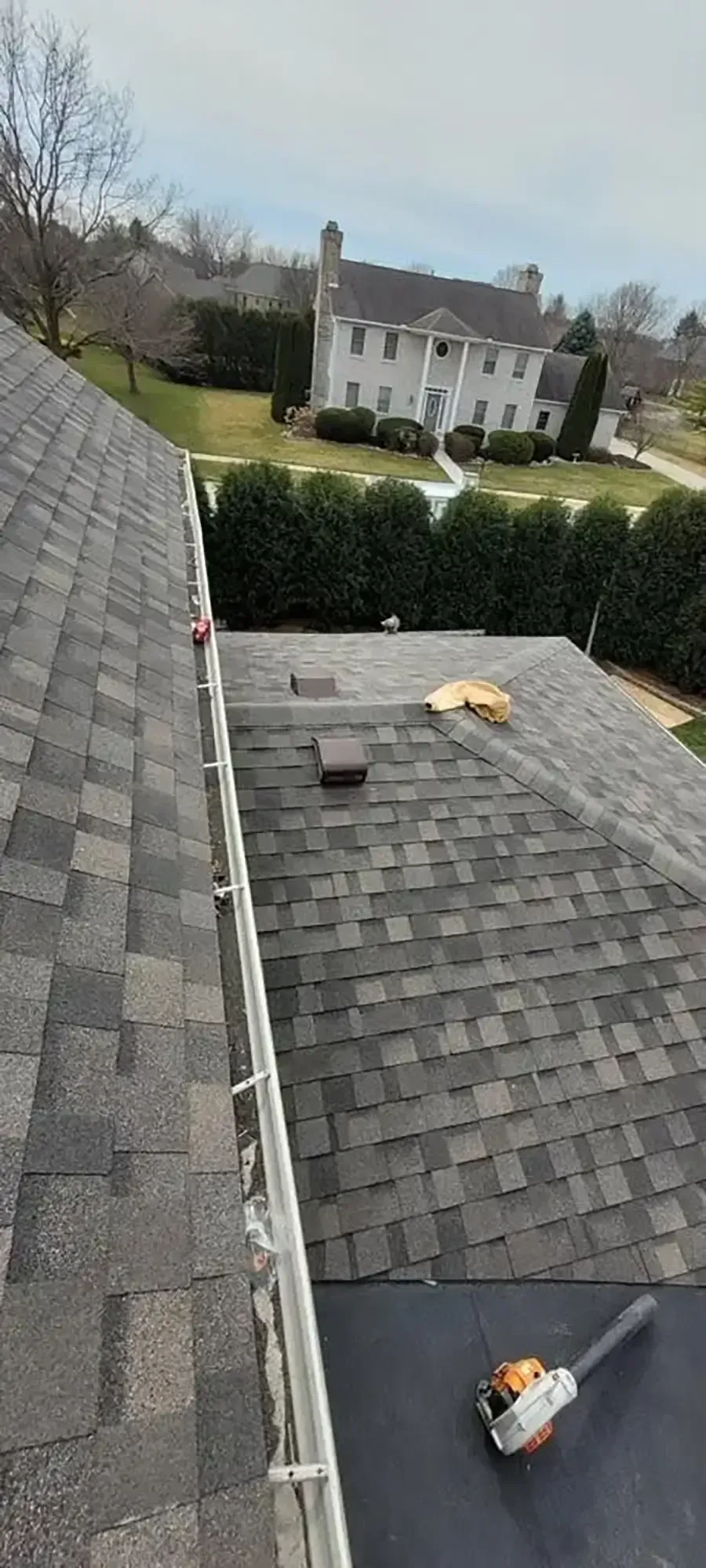 Roof shingles and a small roof repair area overlooking a suburban house and yard