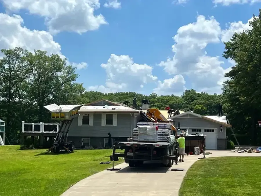 Tree service truck with a bucket lift in a grassy suburban yard beside a house under a blue sky